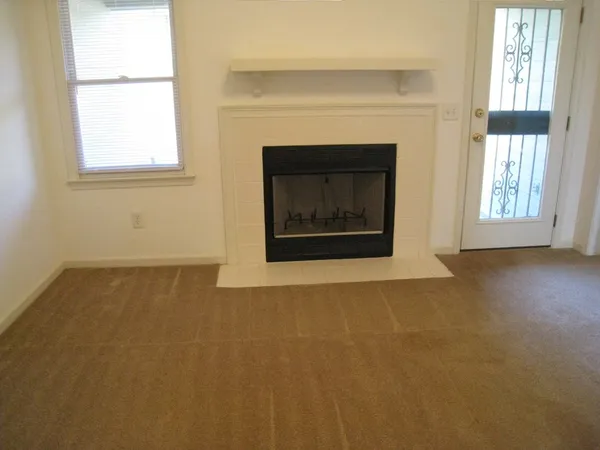 an empty room with windows and fireplace
