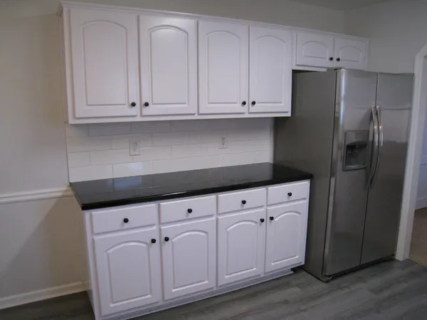 a kitchen with granite countertop white cabinets and refrigerator