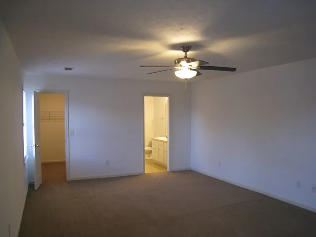 a view of an empty room with a chandelier fan