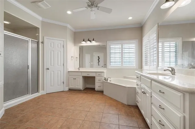 a spacious en suite bathroom with a double vanity sink a large mirror and a bathtub