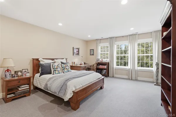 a bedroom with a bed a dresser and a large window