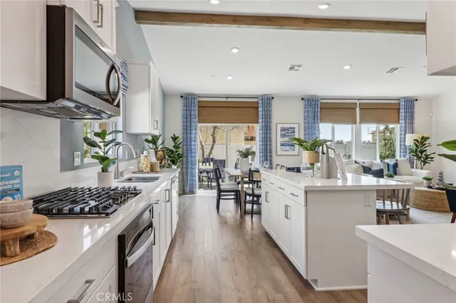 a kitchen with stainless steel appliances a dining table chairs stove refrigerator and cabinets