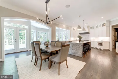 a dining room with stainless steel appliances kitchen island granite countertop a table chairs and a living room