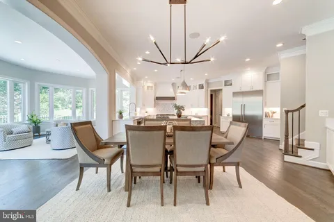 a dining room with stainless steel appliances kitchen island granite countertop a table chairs and a living room view