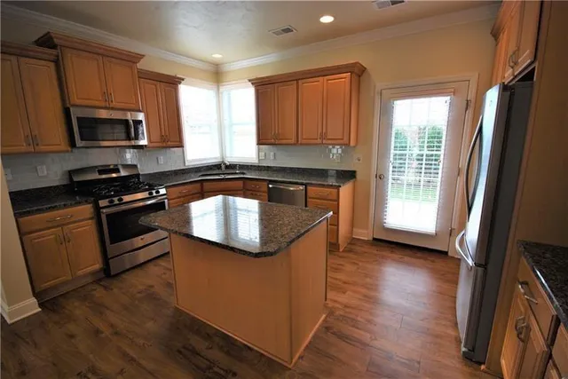 a kitchen with granite countertop a sink wooden floor and stainless steel appliances