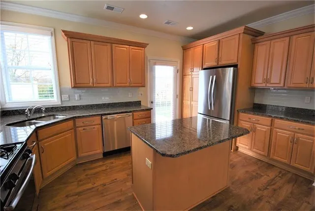 a kitchen with stainless steel appliances granite countertop a refrigerator a sink a stove a microwave and island