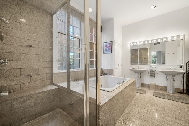 a bathroom with a tub a sink and a large mirror next to a shower