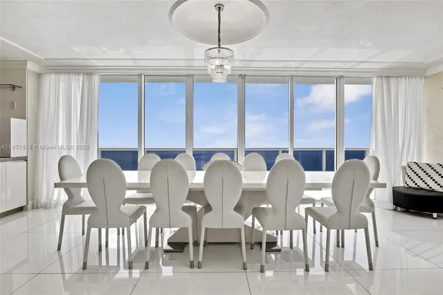 a view of a dining room with furniture a chandelier and large windows