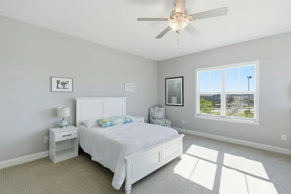 a bedroom with a bed next to a window with a chandelier