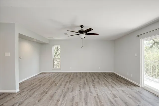a view of empty room with wooden floor and fan