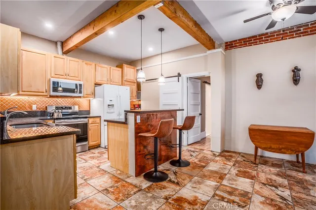 a kitchen with stainless steel appliances kitchen island granite countertop a refrigerator and a stove