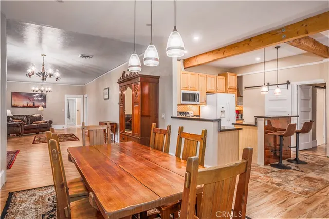 a dining room with wooden floor a chandelier a wooden table and chairs
