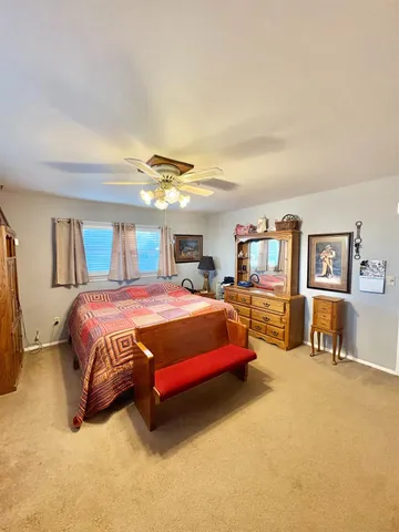 a spacious bedroom with a bed a table and painting on the wall