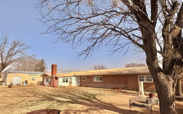a view of a white house with a large tree