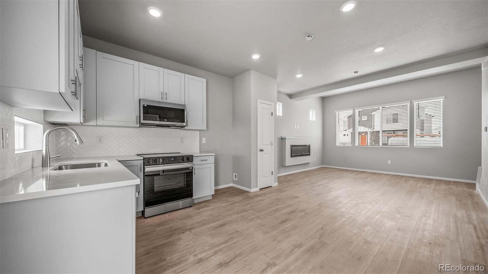 3970 North Rome Street Aurora, CO 80019 - Photo 2 of 22 a kitchen with a sink wooden floor and stainless steel appliances