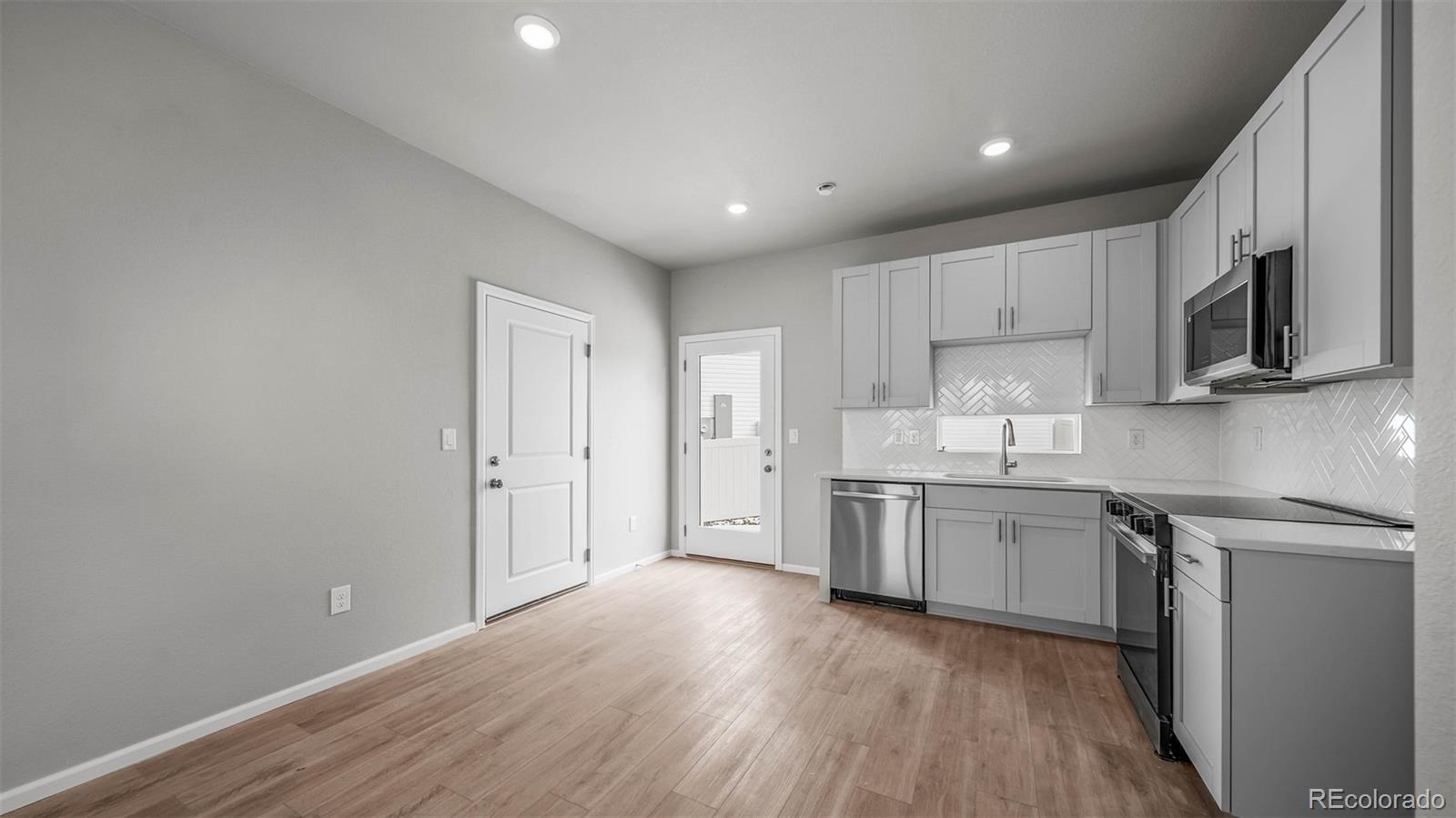 3970 North Rome Street Aurora, CO 80019 - Photo 7 of 22 a kitchen with stainless steel appliances granite countertop a stove a sink and white cabinets with wooden floor