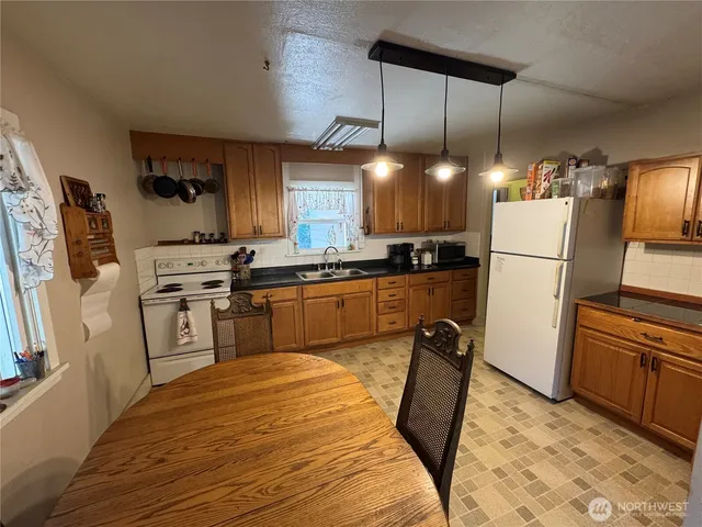 a kitchen with granite countertop a sink a counter space appliances and cabinets