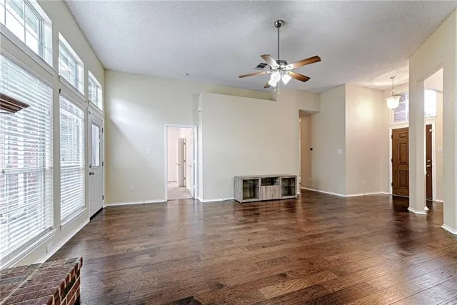 a view of empty room with wooden floor and fan