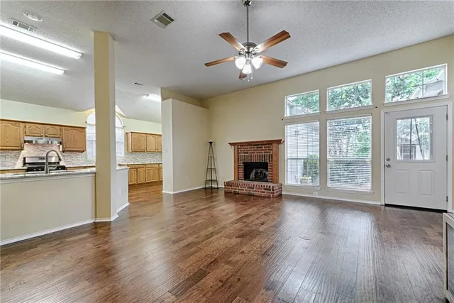an empty room with wooden floor fireplace and windows