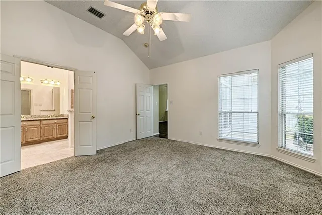an empty room with chandelier fan and windows
