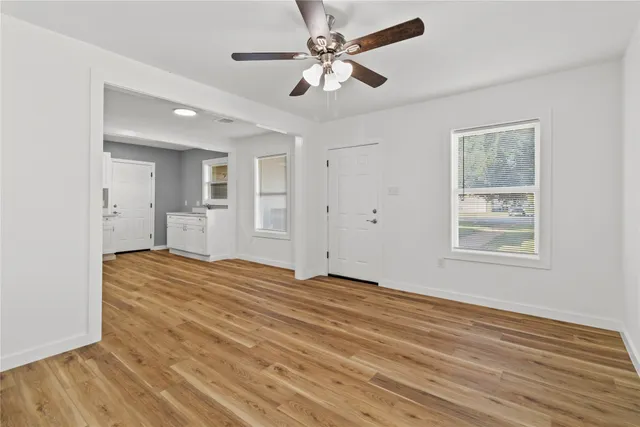 a view of empty room with wooden floor and fan