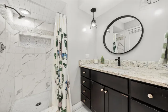 a bathroom with a granite countertop sink a mirror and shower
