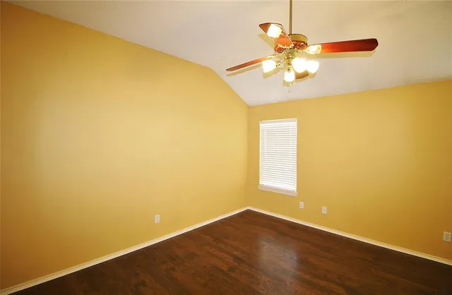 a view of an empty room with chandelier fan and wooden floor