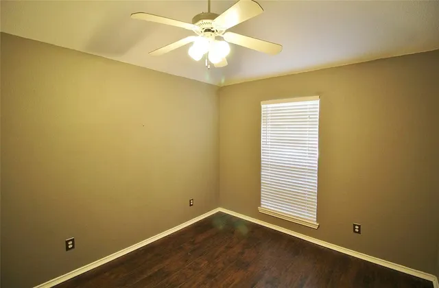 an empty room with a window and a fan