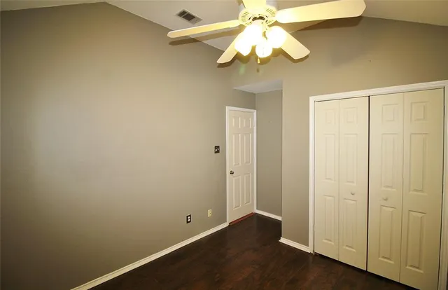 an empty room with a chandelier fan and closet