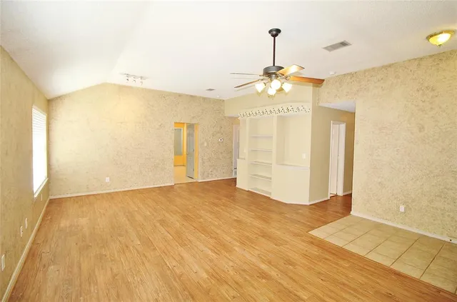 a view of empty room with wooden floor and fan
