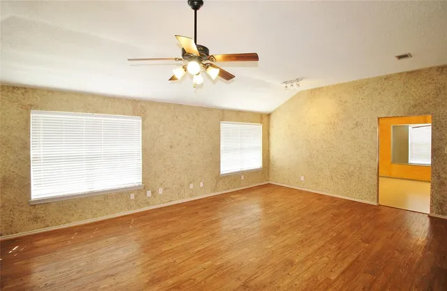 a view of an empty room with wooden floor and a window