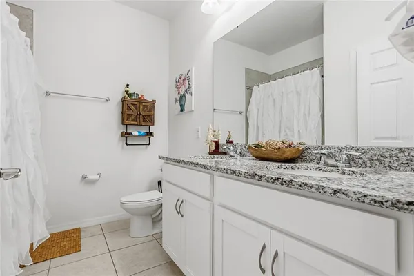 a bathroom with a granite countertop sink and a toilet