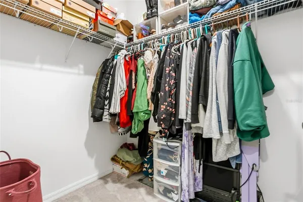 a view of walk in closet with clothes and shoes