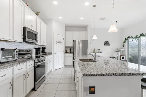 a kitchen with stainless steel appliances granite countertop a sink a stove top oven a refrigerator and a granite counter tops