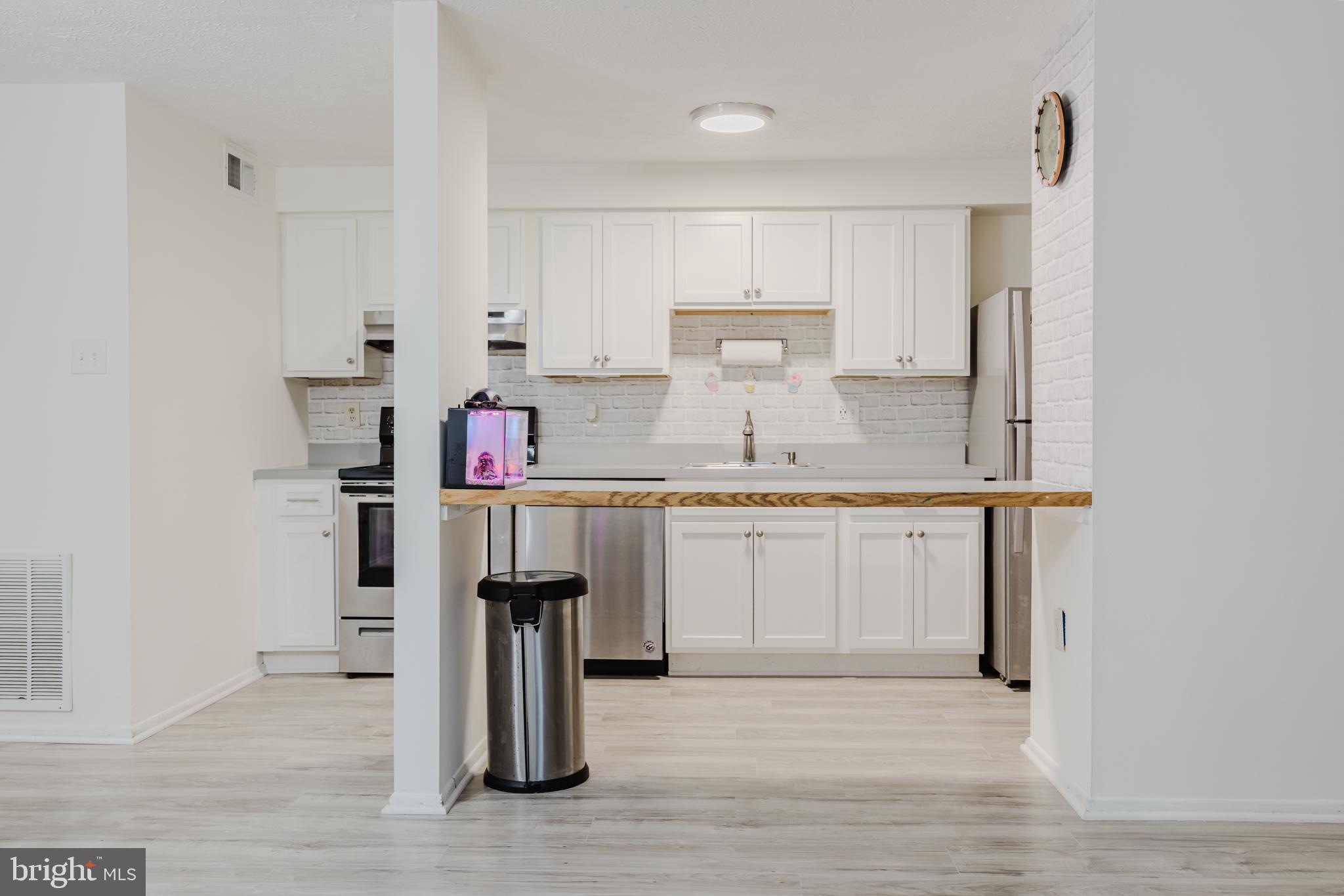 19621 Gunners Branch Road, Unit 823 Germantown, MD 20876 - Photo 21 of 49 a kitchen with kitchen island granite countertop a sink stove and refrigerator