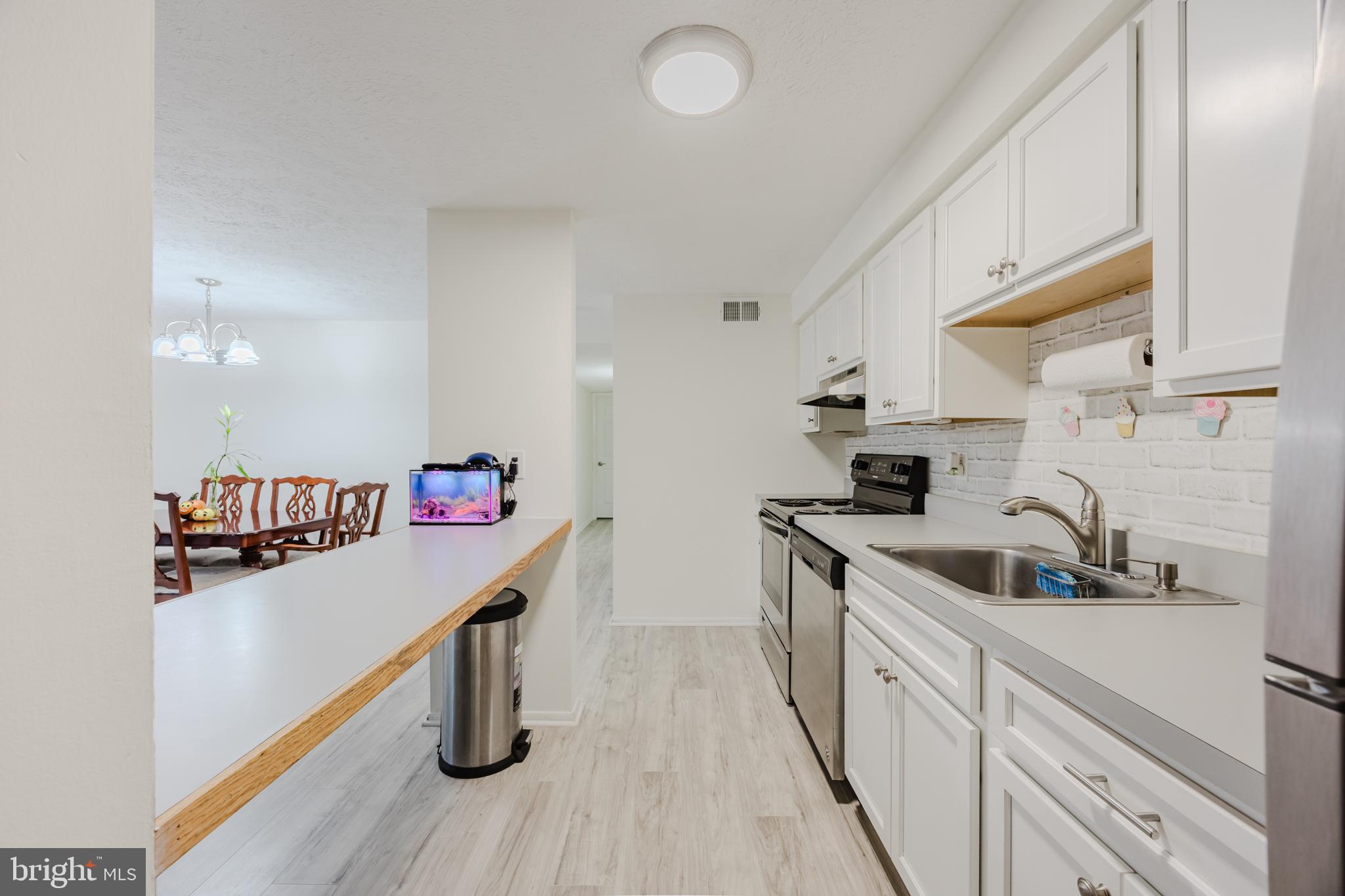 19621 Gunners Branch Road, Unit 823 Germantown, MD 20876 - Photo 25 of 49 a kitchen with kitchen island a sink wooden floor and stainless steel appliances