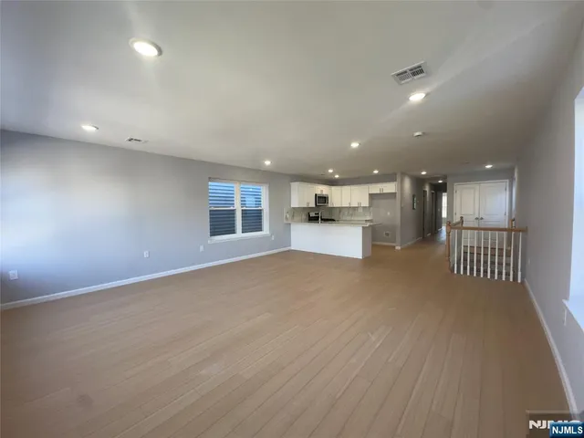 a kitchen with stainless steel appliances granite countertop a stove a refrigerator a sink and white cabinets with wooden floor