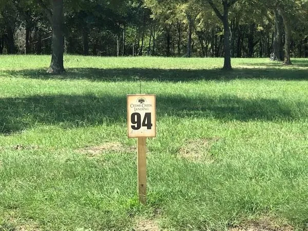 a sign that is sitting in the grass next to a yard