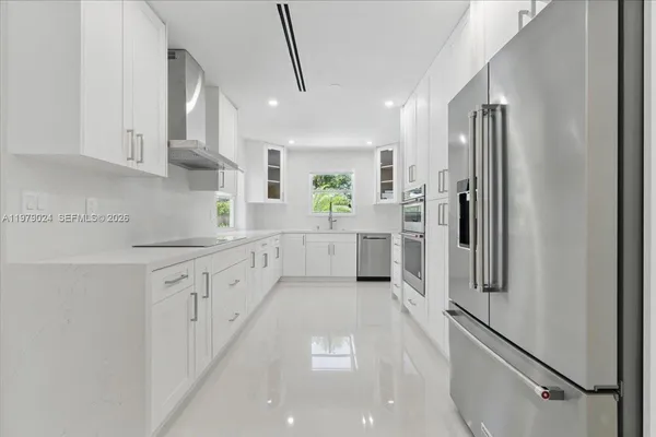 a large kitchen with white cabinets and stainless steel appliances