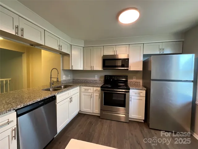 a kitchen with stainless steel appliances granite countertop a refrigerator sink and stove