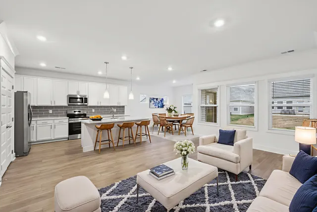 a living room with stainless steel appliances kitchen island granite countertop a couch and white cabinets
