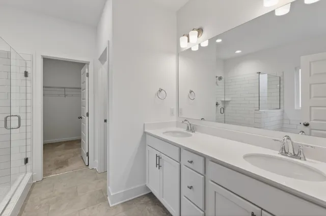 a spacious bathroom with a granite countertop sink a mirror and a shower