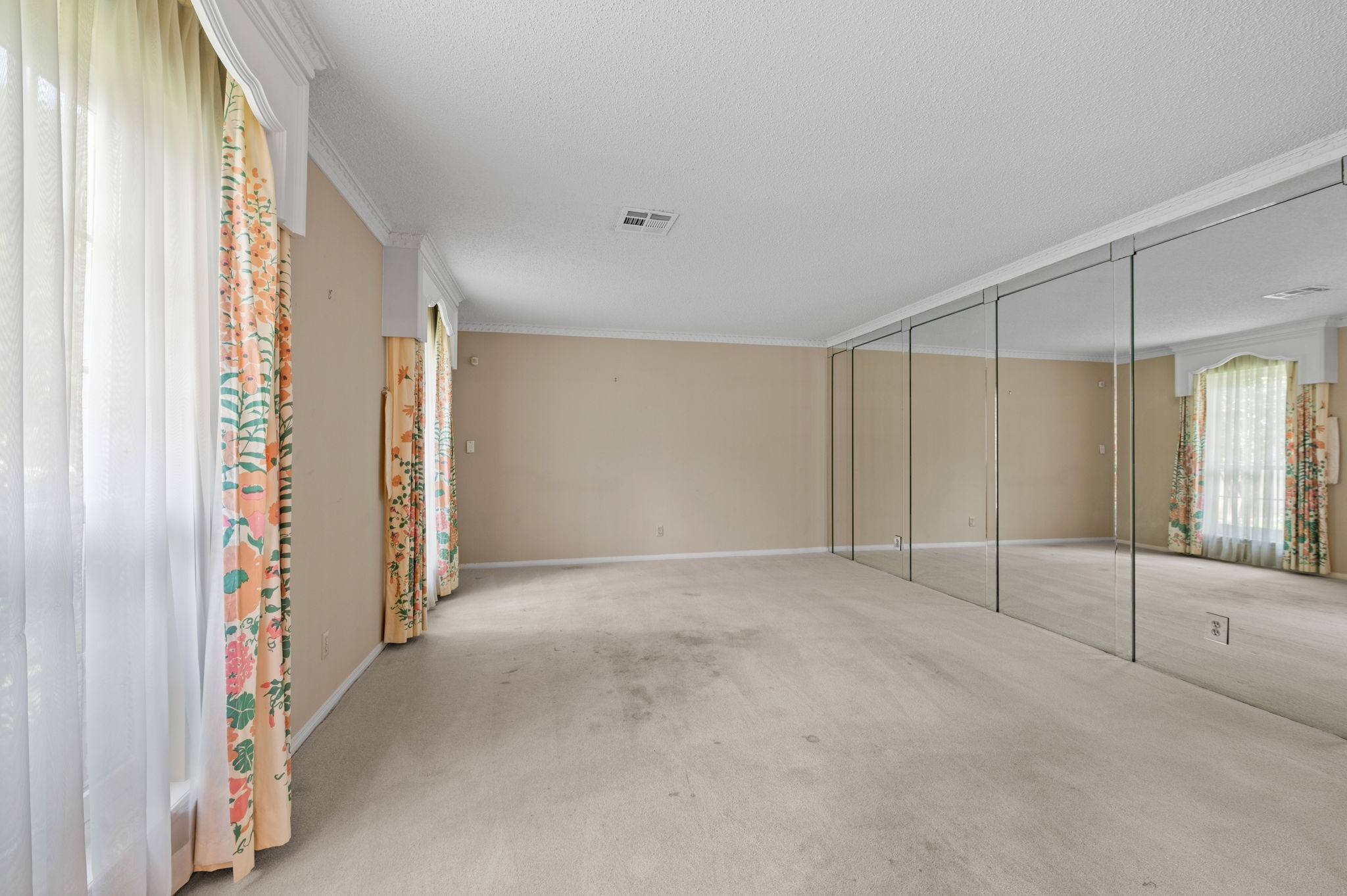Formal living room, overlooking front yard, has a mirrored wall.