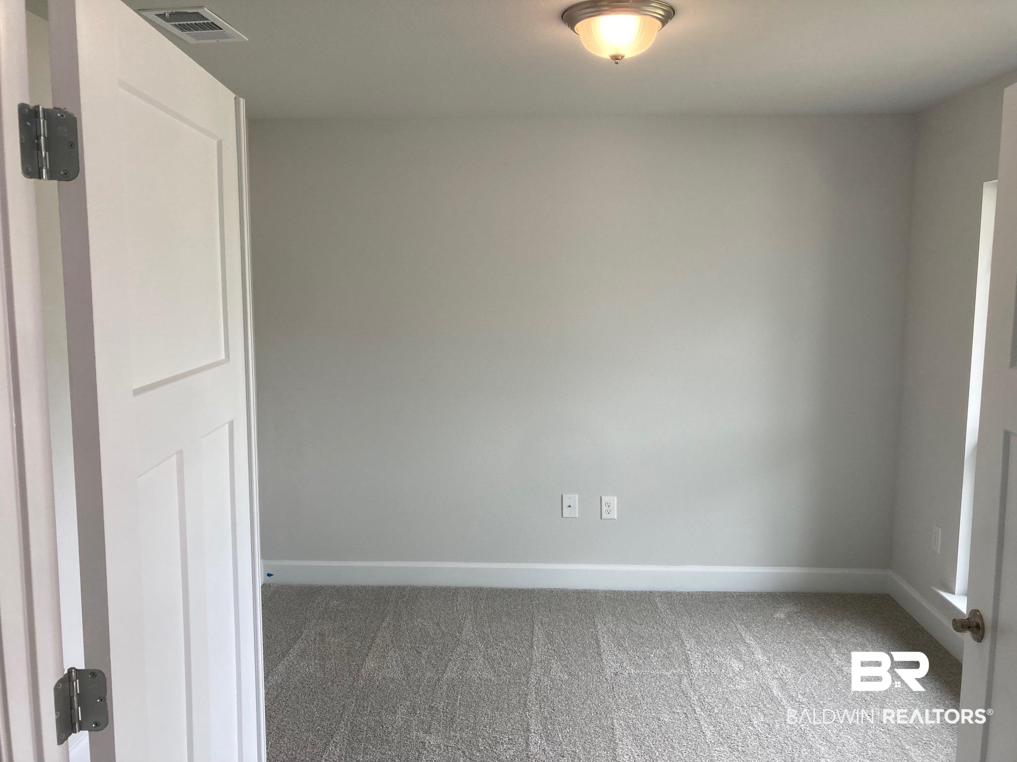 705 Mayflower Drive Foley, AL 36535 - Photo 3 of 19 Carpeted spare room featuring baseboards and visible vents