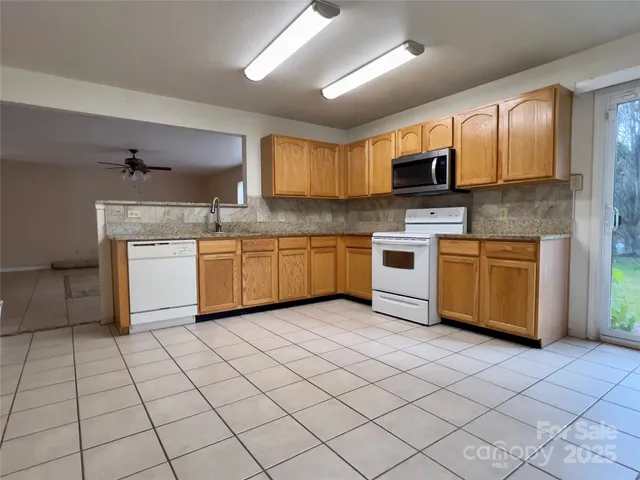 a kitchen with stainless steel appliances granite countertop a sink dishwasher stove top oven and cabinets