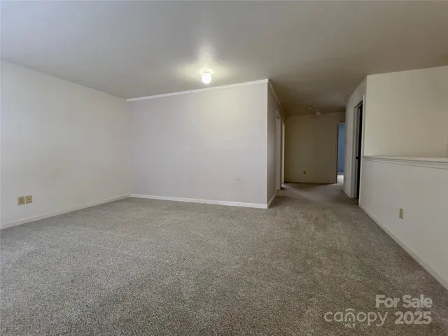 a view of an empty room with chandelier fan and a window