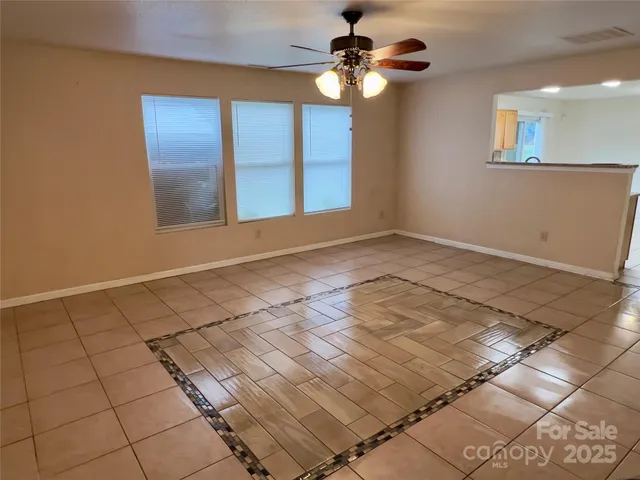 a view of an empty room and window and chandelier fan