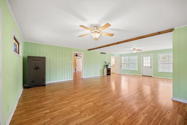 a view of an empty room with window and wooden floor