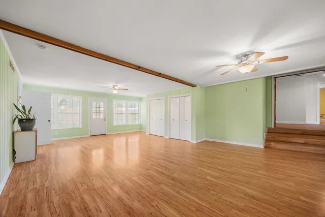 a view of an empty room with window and wooden floor