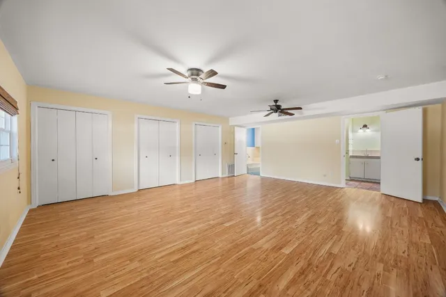a view of empty room with wooden floor and ceiling fan